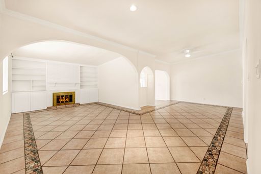 A large empty room with white walls and tiled floors in a brand new house