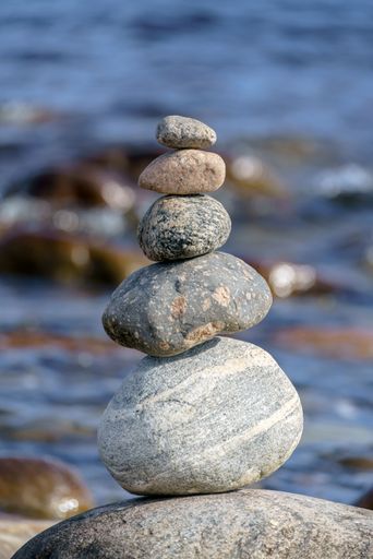 A vertical shot of a pyramid of stones with unstable balance on the beach in daylight