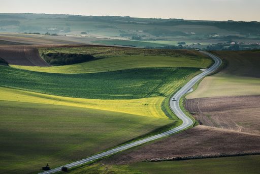 A high angle shot of a narrow freeway in the middle of a green field