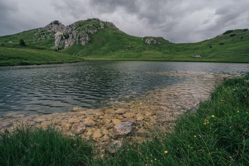 Lago di Valparola, Dolomites, Italy. Alpine mountain lake with green pastures and grass around. Dramatic sky over a mountain lake.