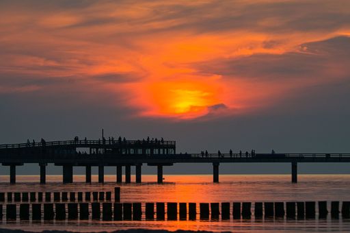 Breathtaking scenery of people at new Heiligenhafen pier on the Baltic Sea, admiring the colorful sunset over sea
