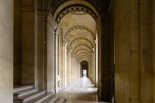 A mesmerising  wide shot of a long corridor with archs near the Louvre museum, Paris, France