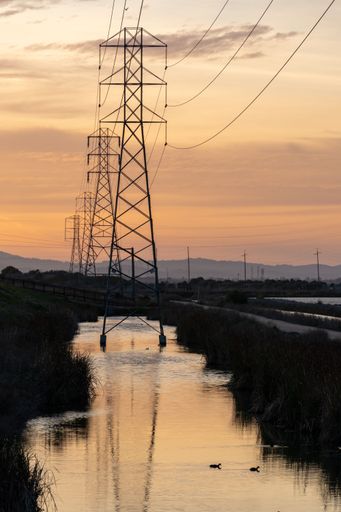 A vertical shot of a transmission towers against the sunset sky