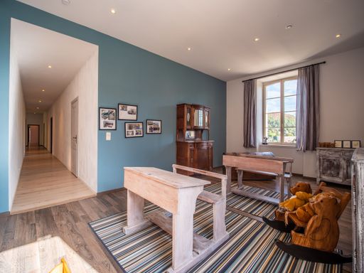 A small bright room for children with desks, carpet, window, blue walls and toys