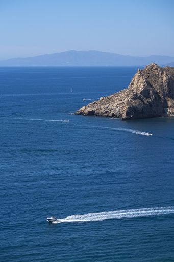 A vertical shot of boats and cliffs in the sea