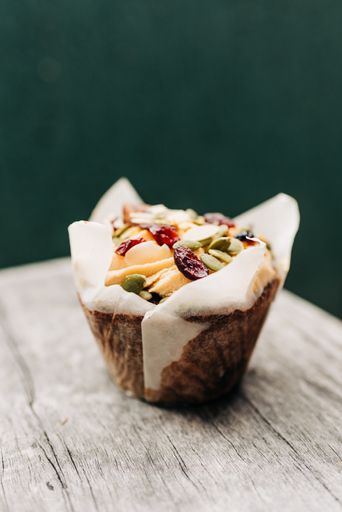 A beautiful closeup shot of a delicious muffin with fruits and pumpkin seeds on a wooden surface