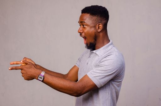 An Afro American man amazed, while presenting with hand and pointing with fingers