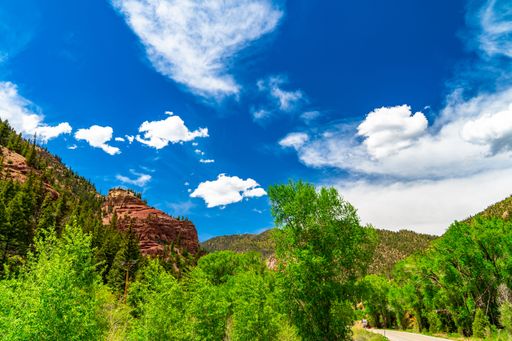 A beautiful landscape of forested mountains against a blue cloudy sky on a sunny day in Colorado