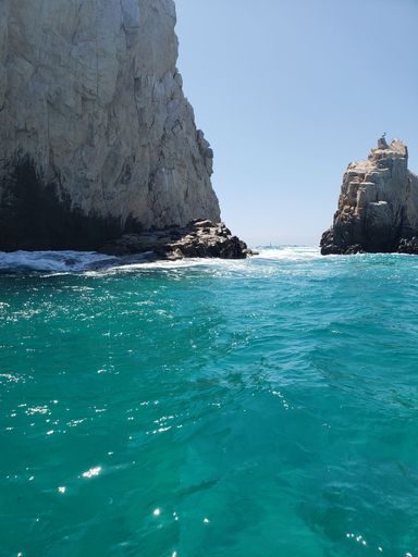 A vertical shot of white rock formation in blue clear water on a sunny day