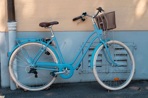 A blue vintage bicycle leaning on a wall