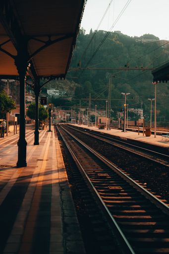 A vertical shot of a train track and an empty platform during the sunrise in Taormina