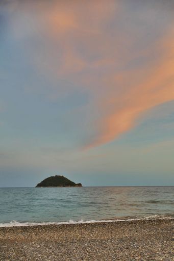 A vertical shot of turtle-shaped Gallinara island from the beach during the sunset in Liguria, Italy