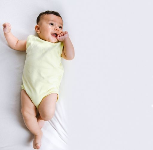 Adorable baby boy in a yellow bodysuit lying on a white background