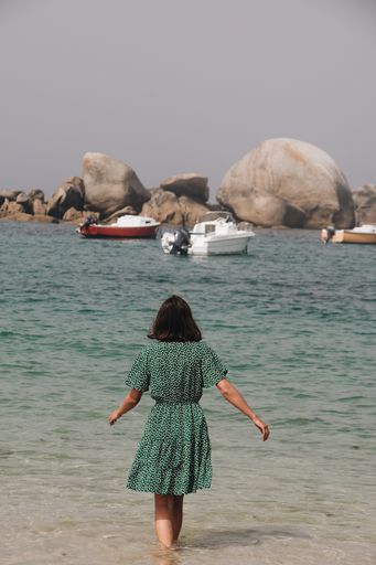 A beautiful vertical shot from behind of a woman walking into the sea