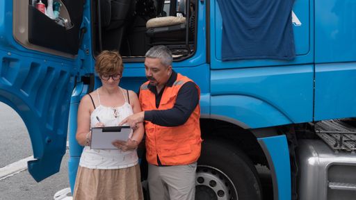 A male construction worker  in an orange vest explaining a contract to a female client