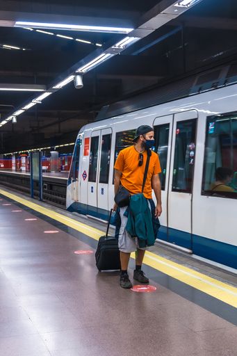 A vertical shot of a young man in a train station wearing a sanitary mask-concept of the new normal