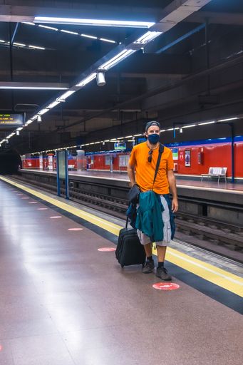 A vertical shot of a young man in a train station wearing a sanitary mask-concept of the new normal