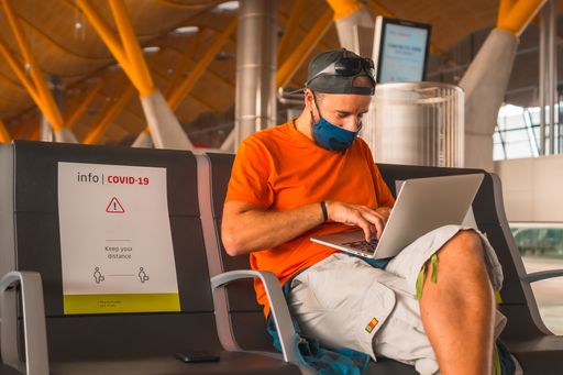 A closeup shot of a young man working on a laptop in an airport