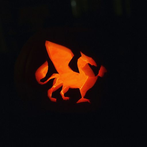 A closeup of light shining through the carved dragon on Halloween pumpkin on a dark background