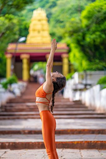 A vertical shot a Caucasian woman doing yoga poses inside an Indian temple