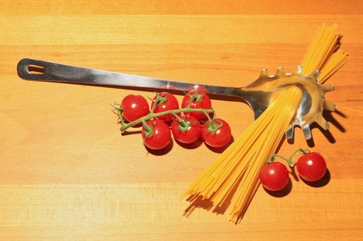 fresh tomatoes and spaghetti noodles pasta with a spoon on a wooden background table, Italy