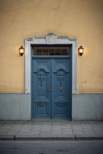 A vertical shot of vintage doors with lanterns on both sides