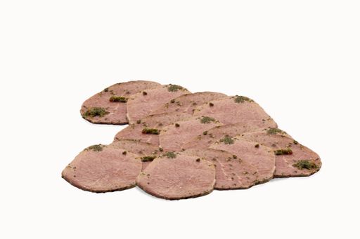 A shot of sliced beef topped with parsley isolated on a white background