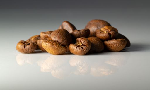 A pile of brown coffee beans on a white table background