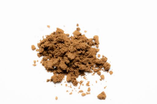 A pile of ground brown coffee beans on a white table background