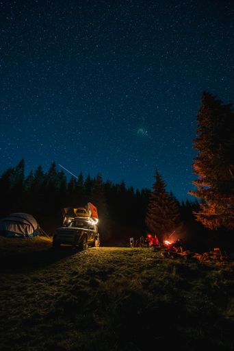 A mesmerizing vertical view of a camping site in the Apuseni Mountains with a beautiful starry night sky