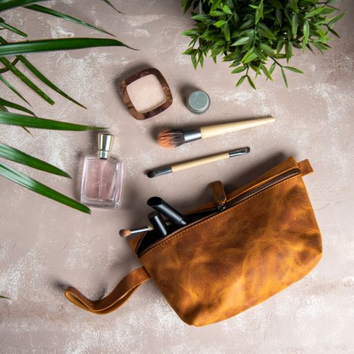 A top view of handmade leather makeup bag with brushes next to it