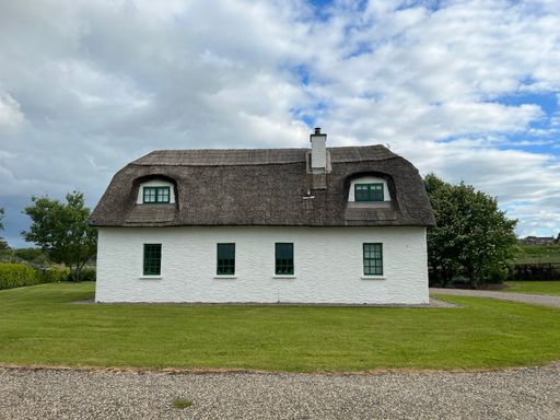 A white house with black roof in Galway Ireland under the cloudy sky
