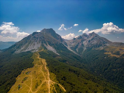An aerial shot of green-covered mount Komovi under the blue sky in  Montenegro