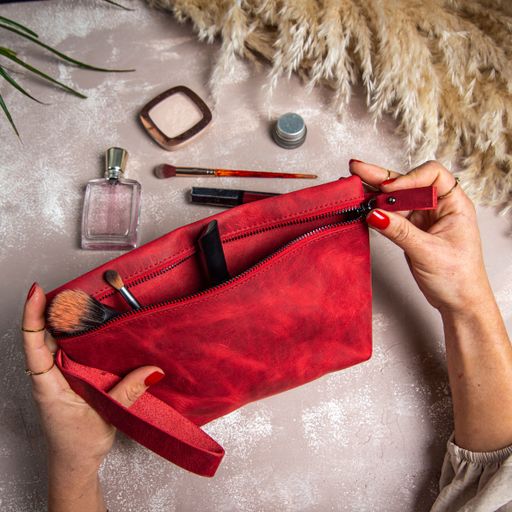 A top view of a woman opening a handmade leather makeup bag on her hands