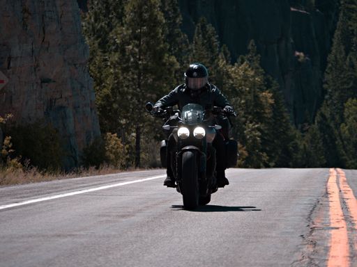 A biker riding a motorcycle on the highway road near the Stone Hill on a sunny day
