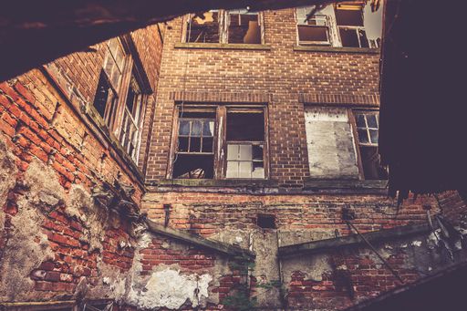 An abandoned weathered brick building exterior with broken windows in France