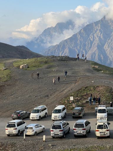 A vertical shot of the mountains with parked cars in Stepantsminda, Georgia