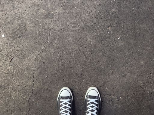 An overhead shot of black sneakers on an asphalt ground - copy space and background