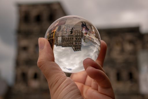 A closeup of a man holding a crystal ball reflecting city buildings