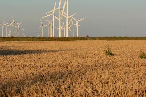 An amazing shot of a beautiful farmland with wind turbines during a sunset