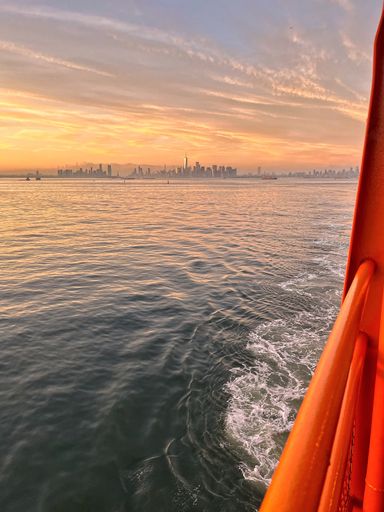 A vertical shot of the New York skyscrapers seen from a boat at dramatic sunset