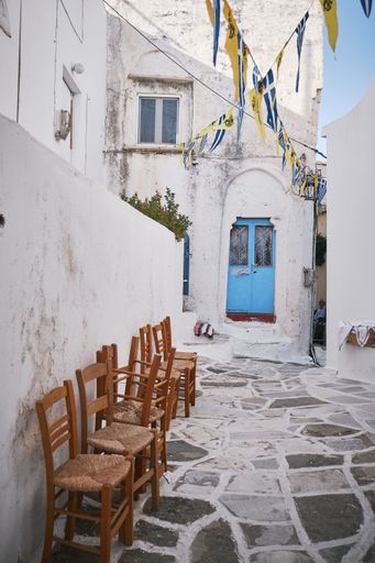 A vertical shot of a beautiful bystreet with flags hanged in the air in Paros, Greece
