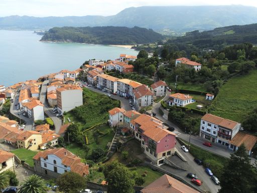 A landscape of Lastres surrounded by the sea and hills covered in greenery in Spain