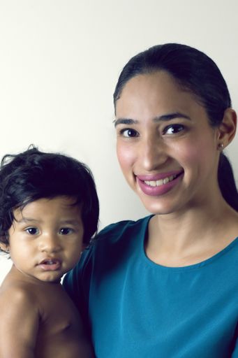 A portrait of a young mother with her son against a white wall