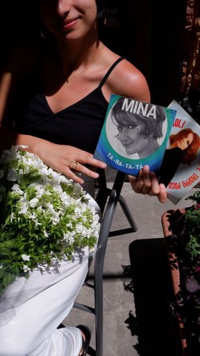 A Caucasian girl holding two vinyl records of Italian singer Mina