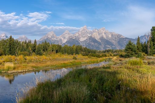 A rvier flowing in a green field with hills on the background in the Grand Teton national park,Wyoming