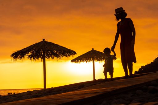 A mother walking on the beach with her son at sunset in Ponta do Sol, Madeira, Portugal.