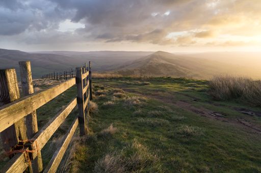 High peak Mam Tor hill in Derbyshire, England captured under sunlight shining through the cloudy sky