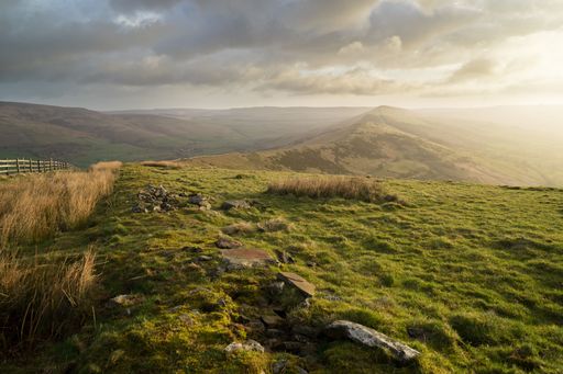 The high peak Mam Tor hill in Derbyshire, England captured under sunlight shining through the cloudy sky