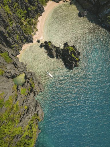 A high angle shot of the ocean and the beach surrounded by moss covered cliffs